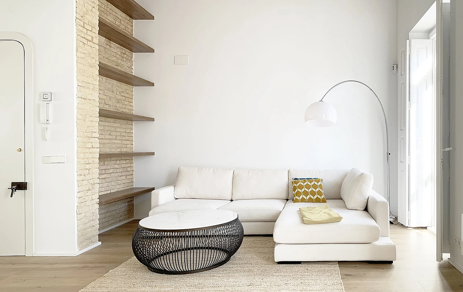Salón reformado con pared de ladrillo visto y estanterías de madera en Ruzafa, Valencia