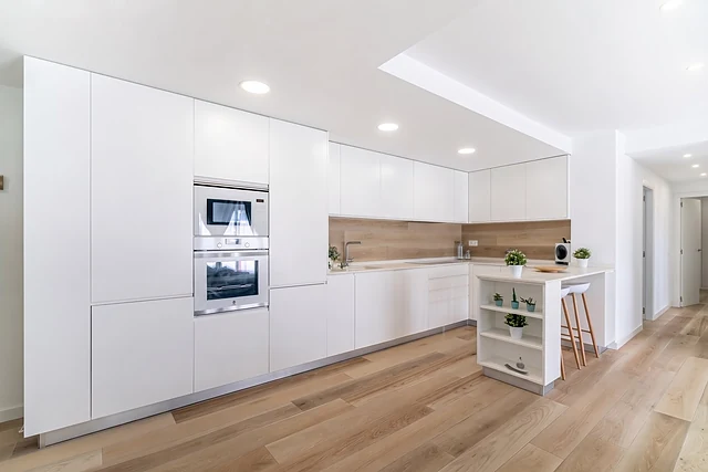 Cocina blanca en L de la Vivienda JYL en Paterna, reforma de Grupo Remodela