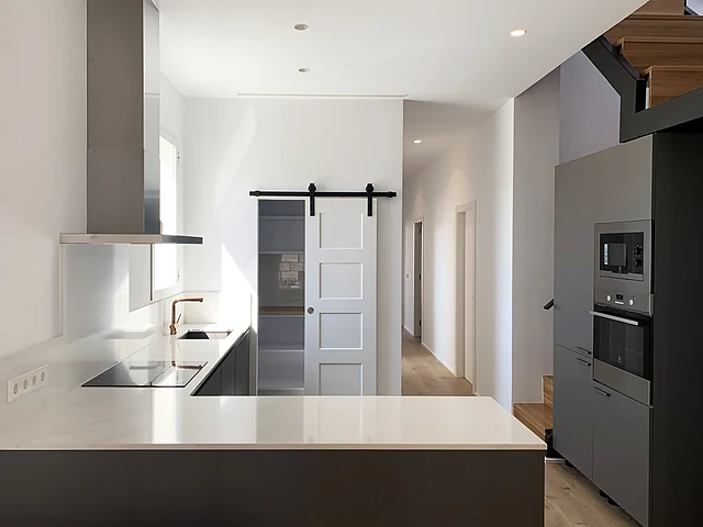 Cocina con encimera blanca y puerta corredera de la Vivienda JYS en Ruzafa, Valencia, reforma de Grupo Remodela