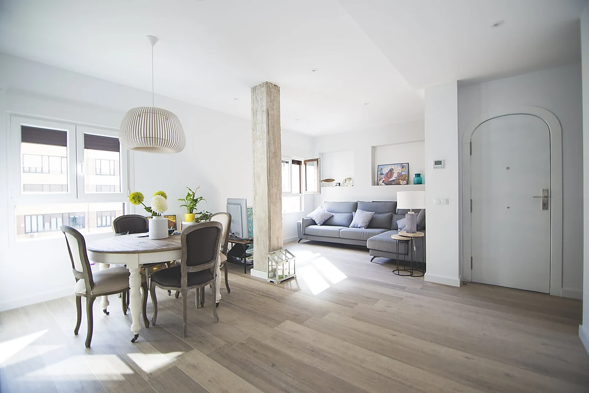 Salón comedor luminoso con suelo de madera en una vivienda reformada en L'Eixample, Valencia