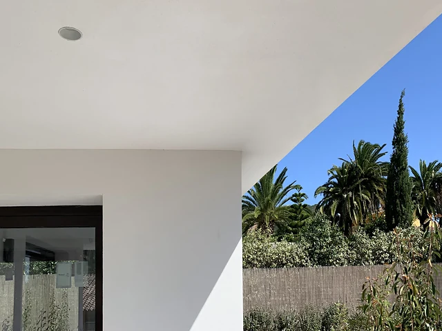 Porche de la vivienda unifamiliar Casa EI en Monasterios, Puzol, con alero blanco y jardín, proyecto de Grupo Remodela